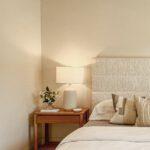 Bett mit Tagesdecke, Nachtschrank, warmem Licht, beigefarbener Tagesdecke Home Staging